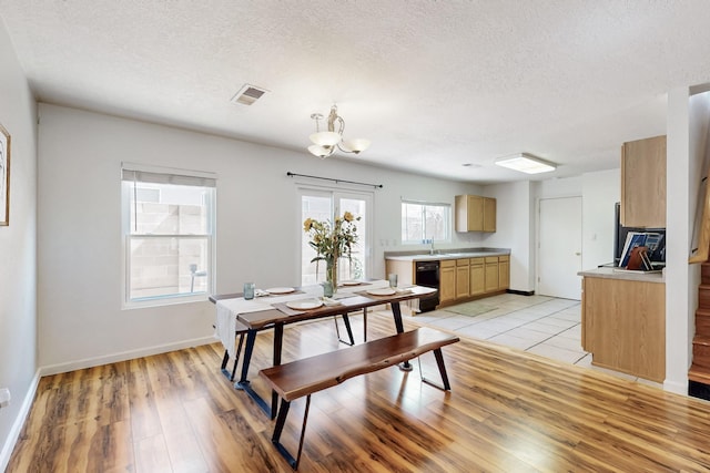 dining area with baseboards, visible vents, light wood-style flooring, a textured ceiling, and a notable chandelier