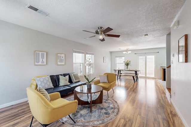 living area featuring visible vents, a textured ceiling, a healthy amount of sunlight, and light wood-style flooring