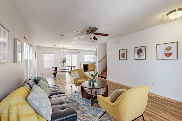 living room featuring ceiling fan, stairway, wood finished floors, and a textured ceiling