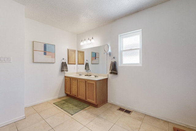 bathroom featuring tile patterned floors, visible vents, a textured ceiling, double vanity, and baseboards