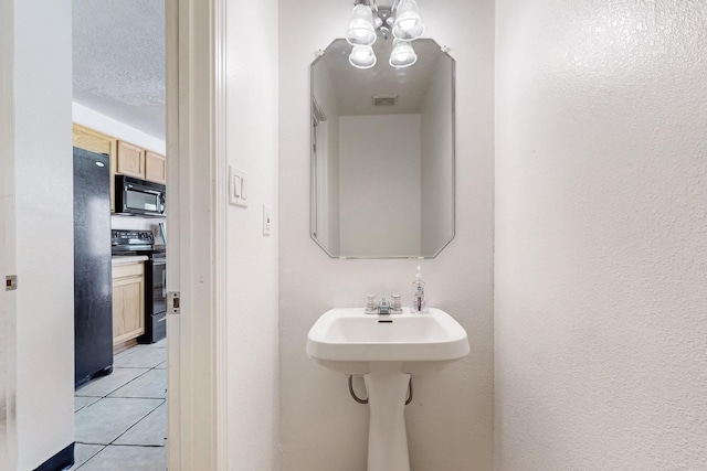 bathroom with tile patterned flooring, visible vents, an inviting chandelier, and a textured wall