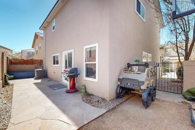 rear view of house featuring a patio, central AC unit, fence, and stucco siding