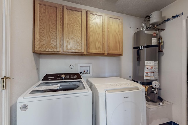 clothes washing area featuring water heater, washing machine and dryer, a textured ceiling, and cabinet space