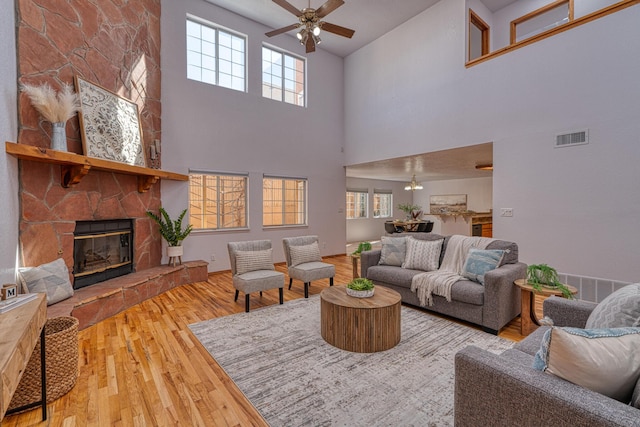 living room with ceiling fan, visible vents, a fireplace, and wood finished floors