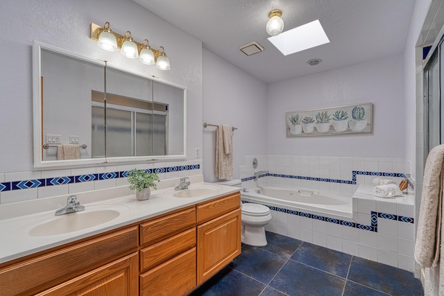 bathroom featuring a garden tub, double vanity, a skylight, and a sink