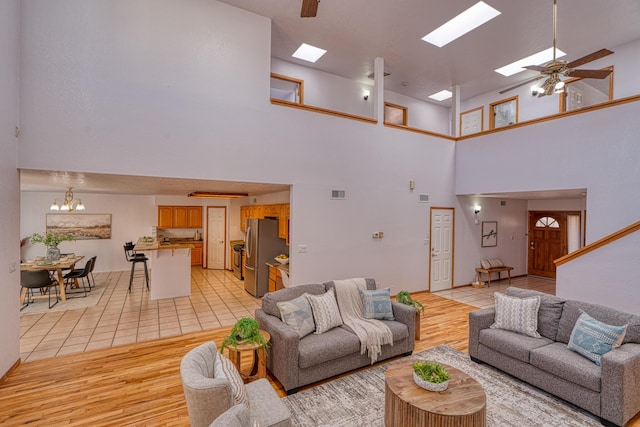 living room with light wood-type flooring, a skylight, and ceiling fan with notable chandelier