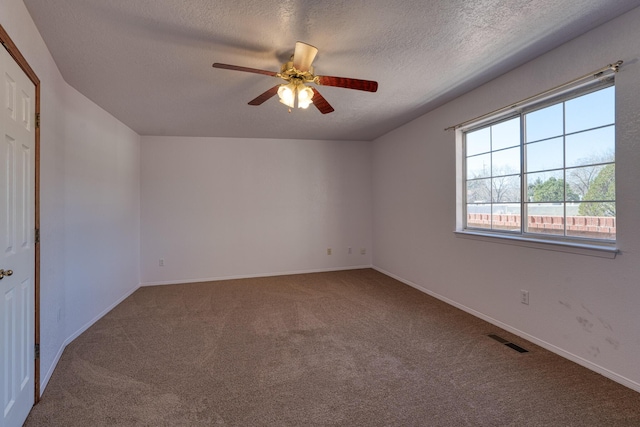 carpeted empty room featuring a textured ceiling, ceiling fan, visible vents, and baseboards