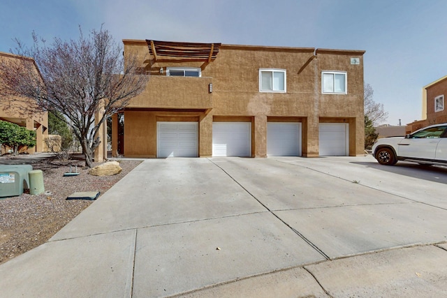 view of front of home with driveway, an attached garage, and stucco siding