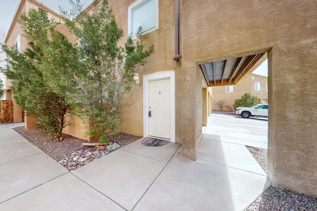 entrance to property featuring fence and stucco siding