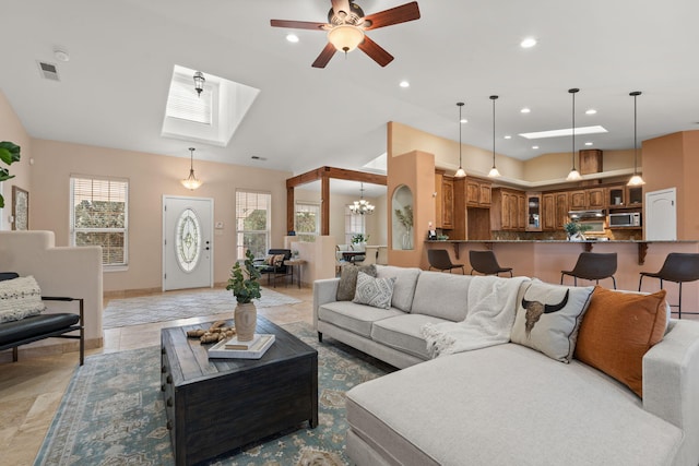 living room with ceiling fan with notable chandelier, a skylight, visible vents, and recessed lighting