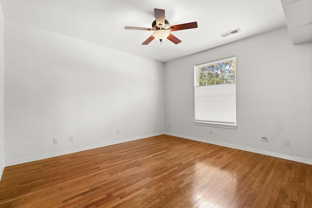 spare room featuring visible vents, hardwood / wood-style floors, a ceiling fan, and baseboards