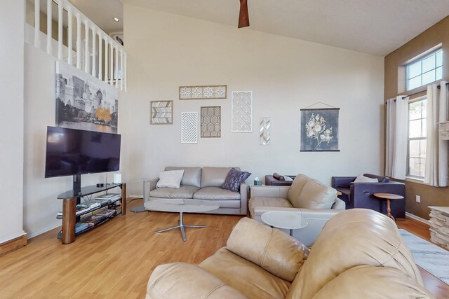 living room with baseboards, high vaulted ceiling, and wood finished floors