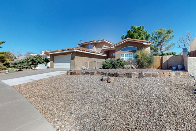 view of front of house featuring a garage, a tile roof, fence, concrete driveway, and stucco siding