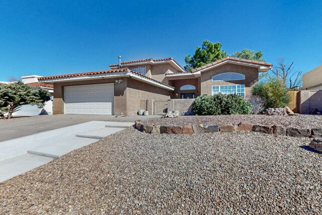 view of front of home featuring a tile roof, stucco siding, fence, a garage, and driveway