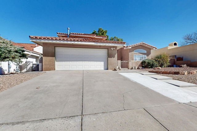 view of front facade with a tiled roof, fence, concrete driveway, and stucco siding