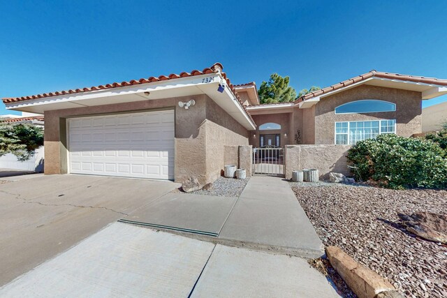 view of front of home featuring a gate, driveway, an attached garage, and stucco siding