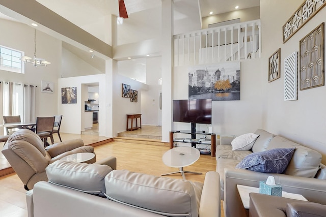 living area with a towering ceiling, an inviting chandelier, wood finished floors, and recessed lighting