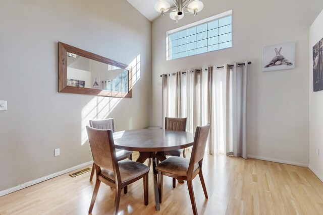 dining room featuring light wood-style floors, baseboards, visible vents, and an inviting chandelier