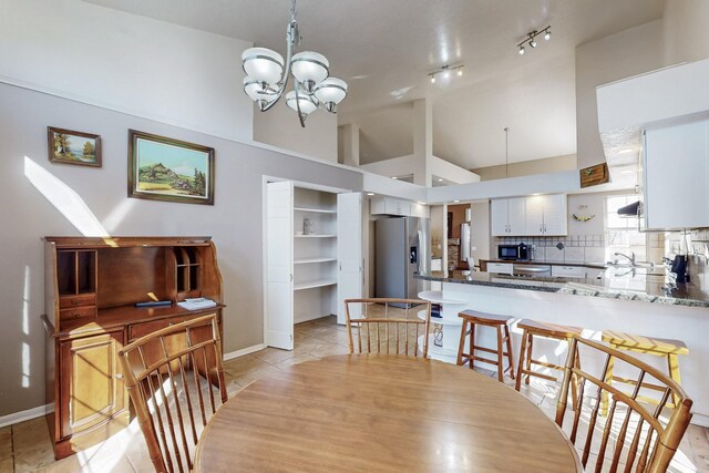 dining area with lofted ceiling, an inviting chandelier, light tile patterned floors, and baseboards