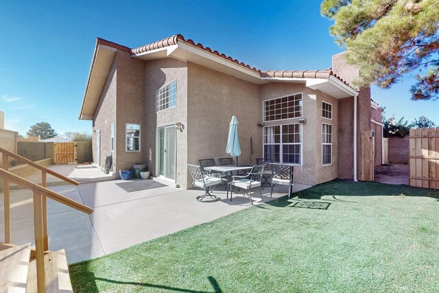 back of property featuring a lawn, a patio, a fenced backyard, a tile roof, and stucco siding