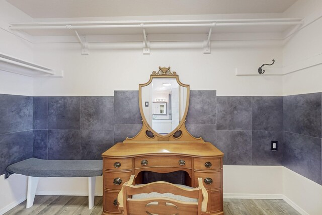 bathroom featuring wood finished floors and tile walls