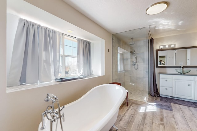 bathroom featuring a freestanding bath, tiled shower, wood finished floors, and vanity