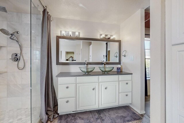 bathroom featuring visible vents, tiled shower, vanity, and wood finished floors