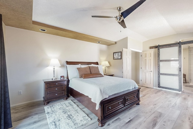 bedroom featuring lofted ceiling, a barn door, baseboards, and light wood-style floors