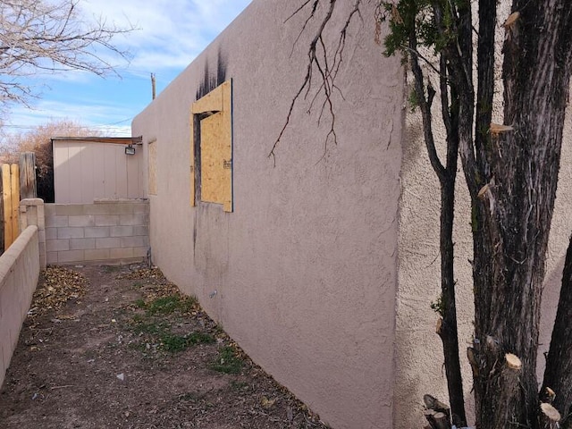 view of side of property with fence and stucco siding