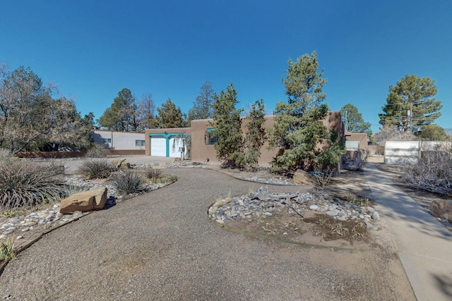 pueblo-style house featuring a garage, driveway, and stucco siding