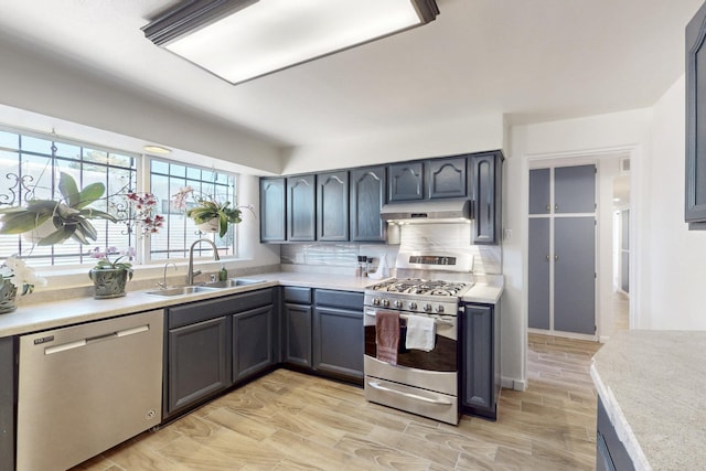 kitchen featuring appliances with stainless steel finishes, light countertops, a sink, and under cabinet range hood