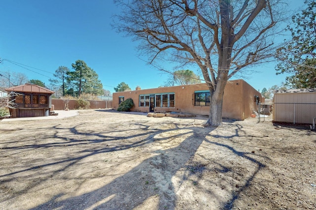 rear view of house featuring fence and stucco siding