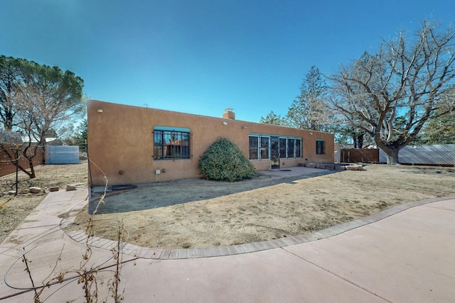 rear view of house featuring fence and stucco siding