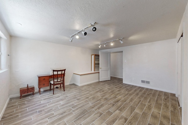 interior space featuring wood tiled floor, visible vents, a textured ceiling, and baseboards