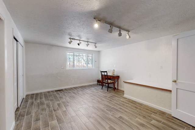 interior space featuring a textured ceiling, wood finished floors, and baseboards