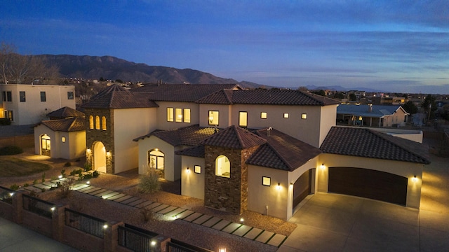 mediterranean / spanish house with a garage, a tiled roof, driveway, and stucco siding