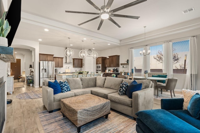 living room featuring arched walkways, recessed lighting, visible vents, baseboards, and light wood finished floors