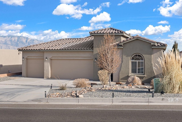 mediterranean / spanish-style house with an attached garage, driveway, a tile roof, and stucco siding