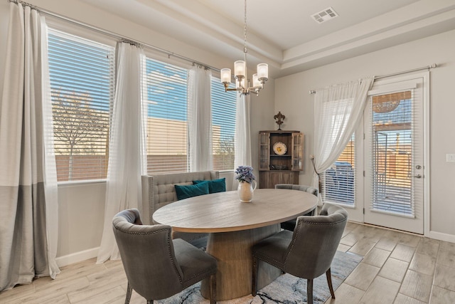 dining area with a notable chandelier, a raised ceiling, visible vents, wood tiled floor, and baseboards