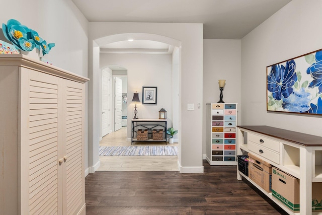 hall with baseboards, arched walkways, and dark wood finished floors