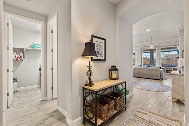 corridor featuring arched walkways, baseboards, and wood tiled floor