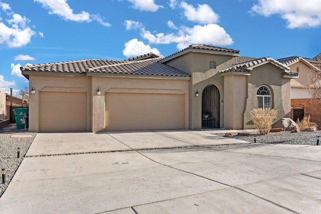 mediterranean / spanish house featuring concrete driveway, a tiled roof, an attached garage, and stucco siding