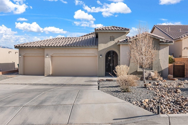 mediterranean / spanish-style house with a garage, a gate, driveway, and stucco siding