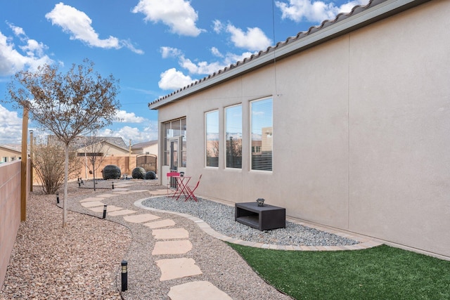 rear view of property with a fenced backyard, a tiled roof, and stucco siding