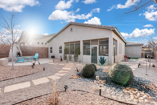 rear view of property with a patio area, a fenced backyard, a sunroom, and stucco siding