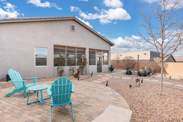 back of property featuring stucco siding, fence, a sunroom, and a patio