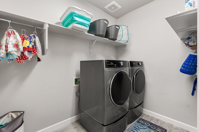 washroom with laundry area, light wood finished floors, washer and clothes dryer, and baseboards