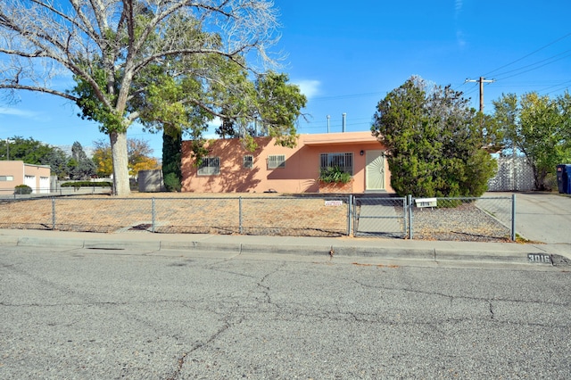 view of front of property with a fenced front yard, a gate, and stucco siding