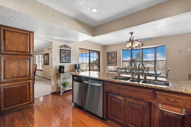 kitchen with a textured ceiling, stone countertops, dark wood-style flooring, a sink, and dishwasher