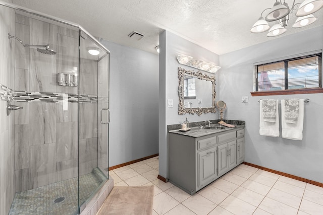 bathroom with baseboards, visible vents, a textured ceiling, vanity, and a shower stall